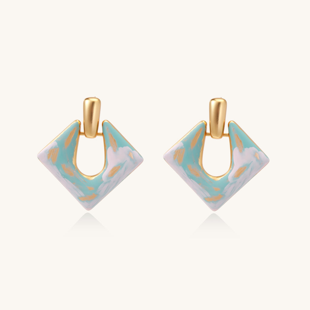 Diamond-shaped gold-plated earrings with pastel marble enamel in turquoise and lavender swirls on beige background