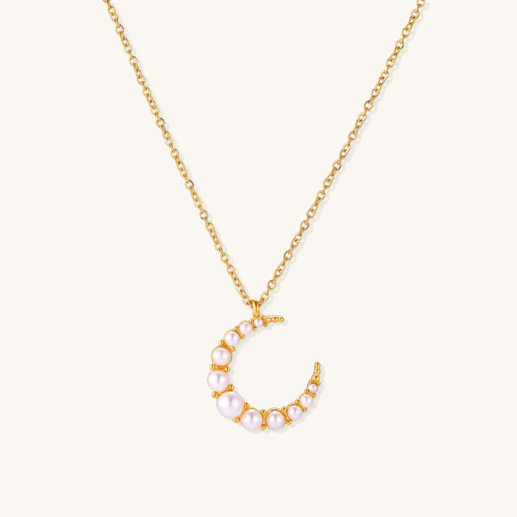 Delicate 18K gold plated necklace featuring crescent moon pendant with white shell pearl beads on neutral background.