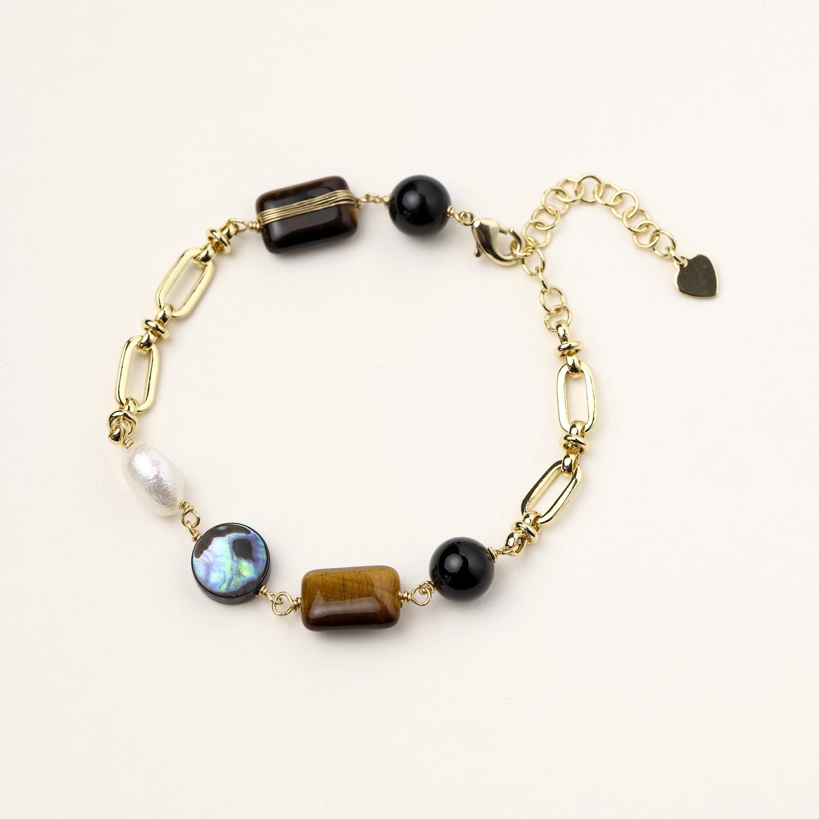 Gold-plated chain bracelet featuring tiger's eye, obsidian, freshwater pearls and abalone shell on white background