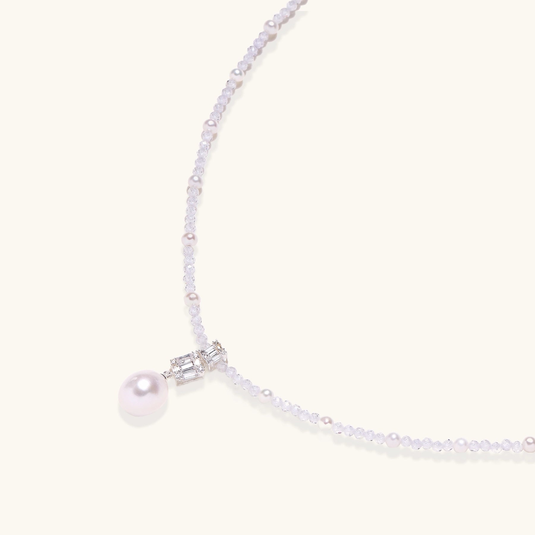 Delicate beaded necklace with lavender crystals, white pearls, and crystal pendant with pearl drop on white background.