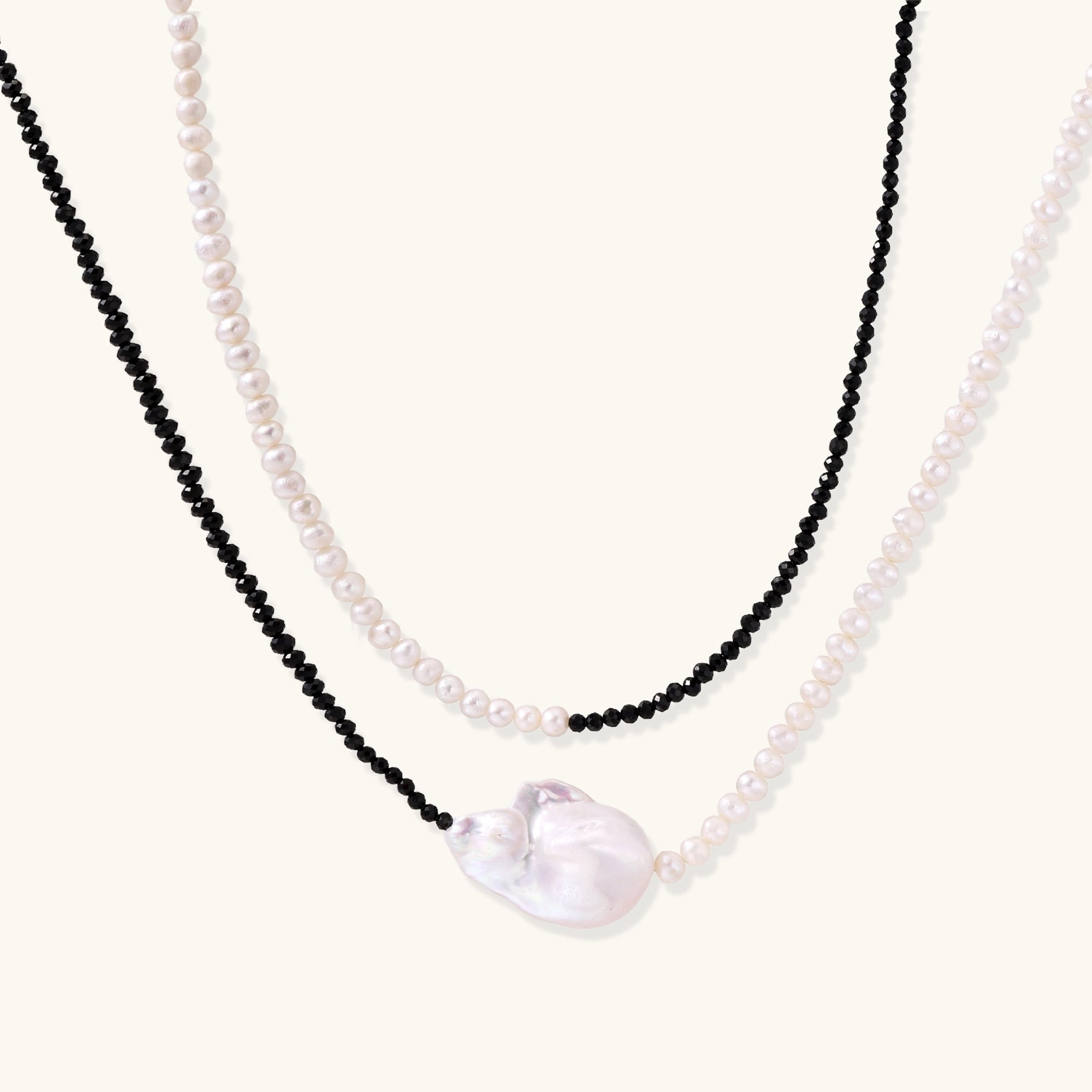Two-strand necklace with black crystal beads and white pearls featuring a large baroque pearl centerpiece on white background.