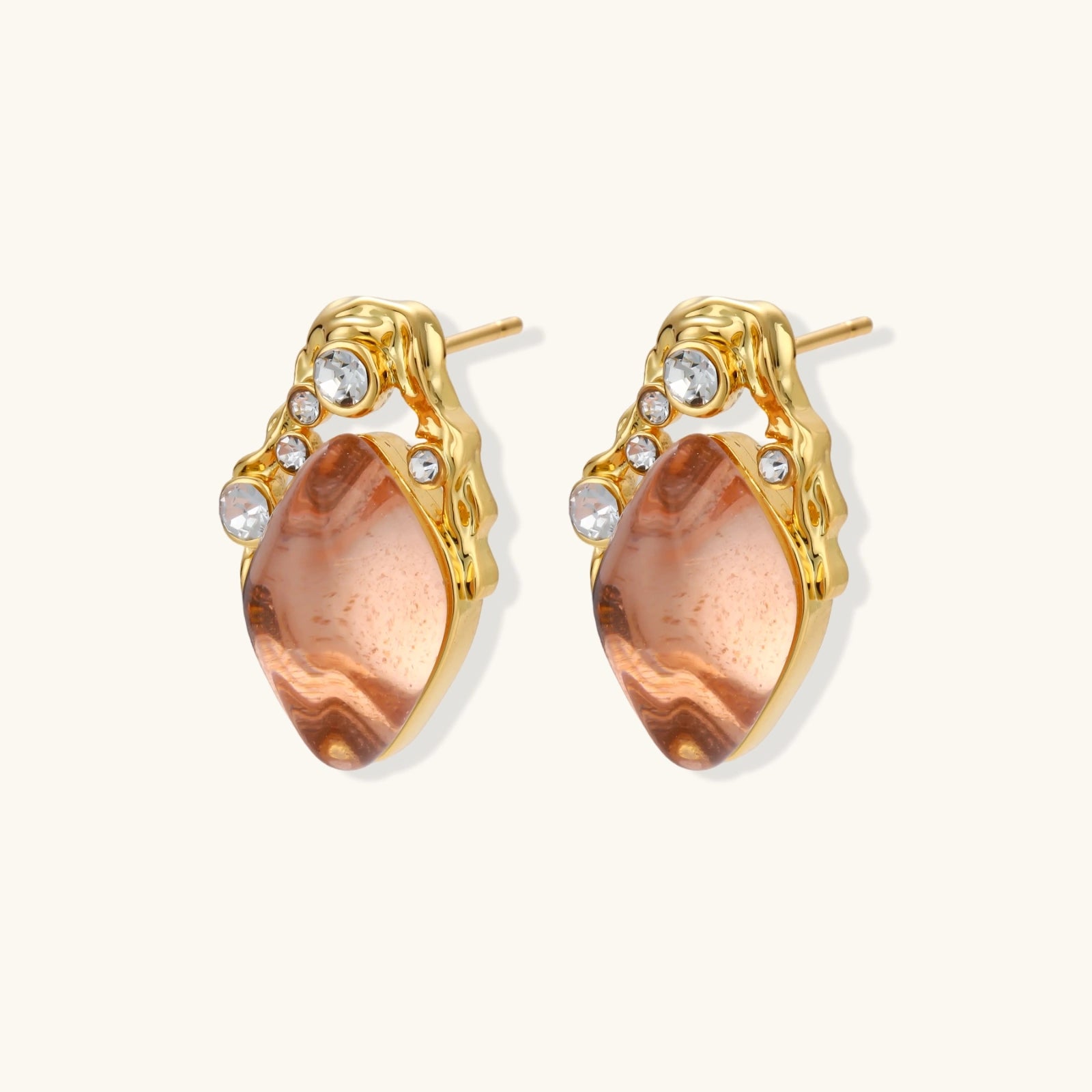 Gold-plated baroque stud earrings with coral-pink liuli stones and cubic zirconia crystals on white background.