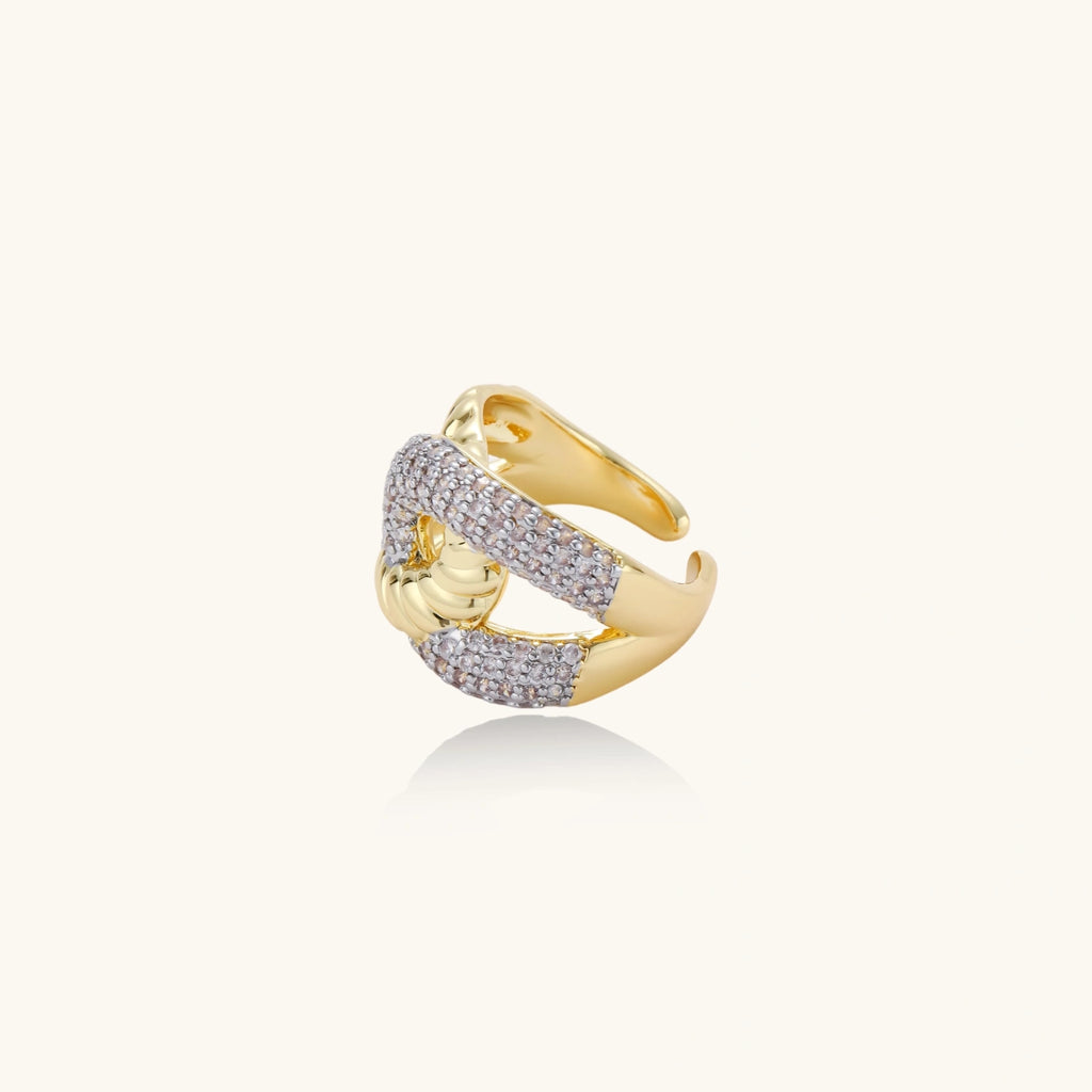 Chunky gold-plated chain-link ring with curved segments and sparkling zirconia crystals on neutral background